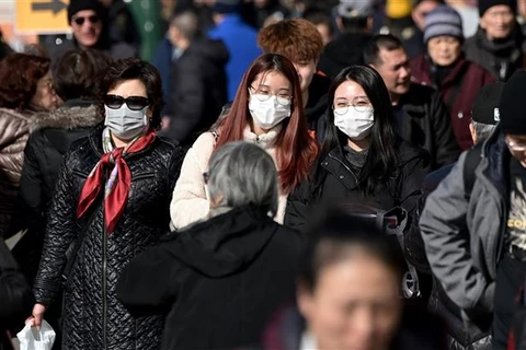 Người dân đeo khẩu trang để phòng tránh lây nhiễm COVID-19 tại New York, Mỹ. (Ảnh: AFP/TTXVN)