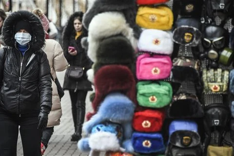 Người dân đeo khẩu trang phòng lây nhiễm dịch COVID-19 trên một đường phố ở Moskva, Nga. (Ảnh: AFP/TTXVN)