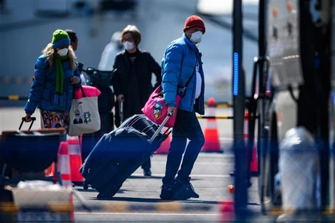 Hành khách lên xe buýt sau khi kết thúc thời gian cách ly và rời khỏi du thuyền Diamond Princess tại cảng Daikoku, Yohohama, Nhật Bản, ngày 21/2/2020. (Ảnh: AFP/TTXVN)