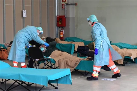Nhân viên y tế điều trị cho bệnh nhân mắc COVID-19 tại một bệnh viện dã chiến ở vùng Lombardy, Italy. (Ảnh: AFP/TTXVN)
