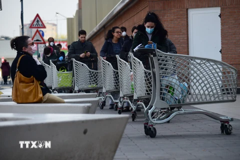 Người dân xếp hàng chờ đợi bên ngoài một siêu thị ở Bologna, Italy ngày 20/3/2020, trong bối cảnh dịch COVID-19 lan rộng. (Ảnh: THX/TTXVN)