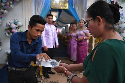 Người dân rửa tay phòng lây nhiễm COVID-19 trước khi dự một lễ cưới ở Phnom Penh, Campuchia. (Ảnh: AFP/TTXVN)