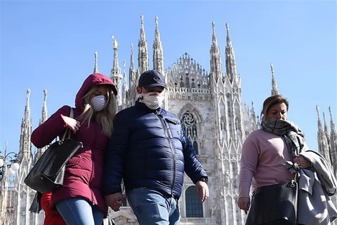 Khách du lịch đeo khẩu trang phòng dịch COVID-19 khi thăm quan Nhà thờ lớn Duomo tại Milan, Italy ngày 24/2/2020. (Ảnh: THX/TTXVN)