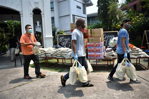 Nhân viên tình nguyện phân phát lương thực, thực phẩm cho người dân bị ảnh hưởng bởi dịch COVID-19 tại Bangkok, Thái Lan. (Ảnh: AFP/TTXVN)