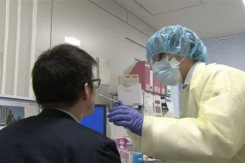 Nhân viên y tế lấy mẫu xét nghiệm COVID-19. (Ảnh: NHK/TTXVN)