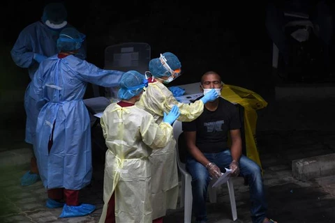Nhân viên y tế lấy mẫu xét nghiệm COVID-19 cho người lao động nước ngoài tại Singapore. (Ảnh: AFP/TTXVN)