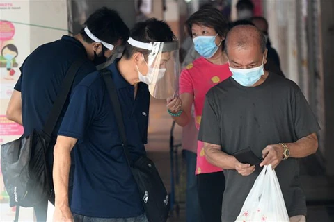 Người dân đeo khẩu trang phòng lây nhiễm COVID-19 tại Singapore. (Ảnh: AFP/TTXVN)