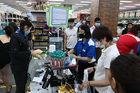 Người dân đeo khẩu trang phòng lây nhiễm COVID-19 khi mua hàng tại siêu thị ở Singapore. (Ảnh: AFP/ TTXVN)