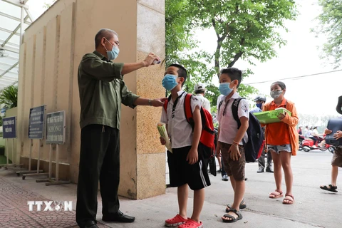 Học sinh Trường Tiểu học Nghĩa Tân, quận Cầu Giấy được kiểm tra thân nhiệt khi tới trường. (Ảnh: Thanh Tùng/TTXVN)