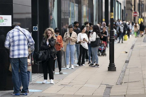 Người dân xếp hàng bên ngoài một cửa hàng tại Manchester, Anh. (Ảnh: THX/TTXVN)