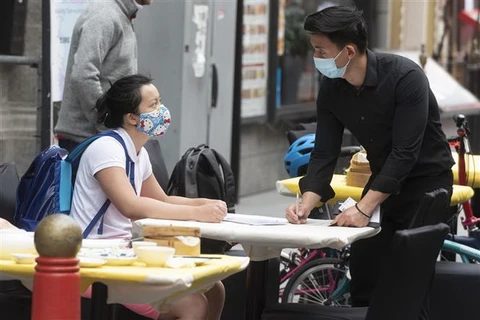 Người dân đeo khẩu trang tại một nhà hàng ở London, Anh. (Ảnh: AFP/TTXVN)