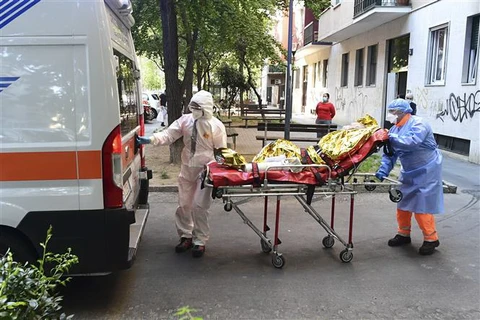 Nhân viên y tế chuyển bệnh nhân COVID-19 tới bệnh viện tại Milan, Italy. (Ảnh: AFP/TTXVN)