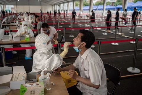 Nhân viên y tế lấy mẫu dịch xét nghiệm COVID-19 cho người dân tại Bắc Kinh, Trung Quốc. (Ảnh: AFP/TTXVN)