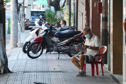Người dân bình thản đọc báo trong khu vực phong tỏa. (Ảnh: Văn Dũng/TTXVN)