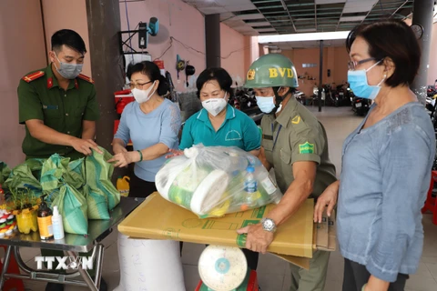 Các tình nguyện viên tiến hành cân gạo cho người dân mang rác nhựa đến đổi. (Ảnh: Hồng Giang/TTXVN)
