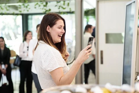 Khách hàng trải nghiệm một mẫu điện thoại thông minh của Samsung tại Sydney, Australia. (Ảnh: Yonhap/TTXVN)