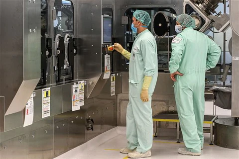 Các kỹ thuật viên giám sát việc sản xuất quy mô lớn và cung ứng vắcxin phòng COVID-19. (Ảnh: AFP/TTXVN)