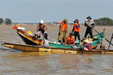 Người dân Lệ Thủy, Quảng Bình chèo thuyền đi lấy hàng cứu trợ do địa hình phức tạp khiến lực lượng chức năng không thể tiếp cận. (Ảnh: Thành Đạt/TTXVN)