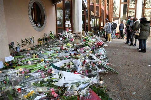 Người dân đặt hoa tưởng niệm thầy giáo Samuel Paty bị đối tượng Hồi giáo cực đoan sát hại, tại trường trung học Conflans-Sainte-Honorine, cách thủ đô Paris của Pháp 30km về phía tây bắc, ngày 17/10/2020. (Ảnh: AFP/TTXVN)