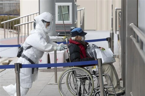Nhân viên y tế đưa bệnh nhân COVID-19 tới trung tâm y tế ở Seoul, Hàn Quốc, ngày 9/12/2020. (Ảnh: THX/TTXVN)