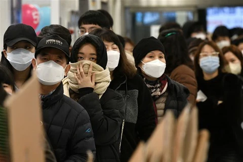 Người dân đeo khẩu trang phòng dịch COVID-19 khi xếp hàng bên ngoài một cửa hàng bán lẻ ở Daegu, Hàn Quốc. (Ảnh: AFP/TTXVN)
