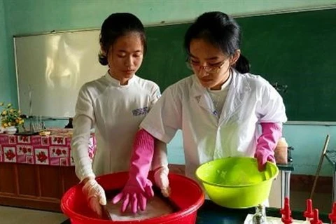 Hai nữ sinh thực hiện công đoạn sản xuất giấy theo phương pháp thủ công trong phòng thí nghiệm.
