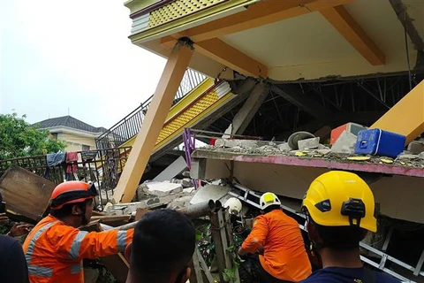 Lực lượng cứu hộ tìm kiếm nạn nhân dưới đống đổ nát của tòa nhà bị sập sau trận động đất tại đảo Sulawesi, miền Trung Indonesia ngày 15/1/2021. (Ảnh: AFP/TTXVN)