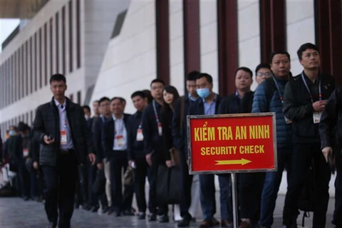 Phóng viên các cơ quan báo chí xếp hàng để qua kiểm tra an ninh trước khi vào hội trường Trung tâm Hội nghị Quốc gia. (Ảnh: TTXVN)
