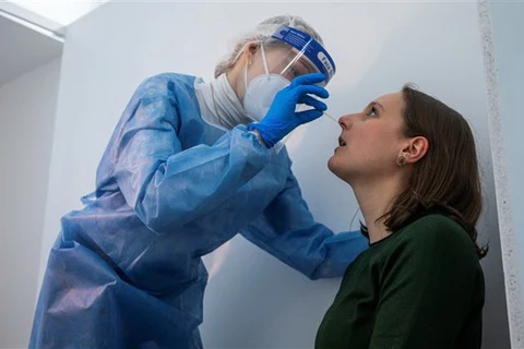 Nhân viên y tế lấy mẫu xét nghiệm COVID-19 cho người dân ở Berlin, Đức. (Ảnh: AFP/TTXVN)