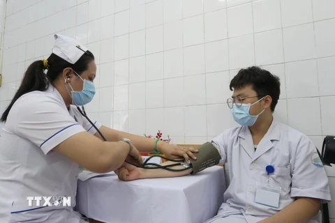 Nhân viên y tế Bệnh viện Bệnh Nhiệt đới Thành phố Hồ Chí Minh được khám sàng lọc trước khi tiêm vaccine phòng COVID-19. (Ảnh: Đinh Hằng/TTXVN)