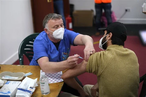 Nhân viên y tế tiêm vaccine ngừa COVID-19 cho người dân tại điểm tiêm phòng ở London, Anh (Ảnh: AFP/TTXVN)