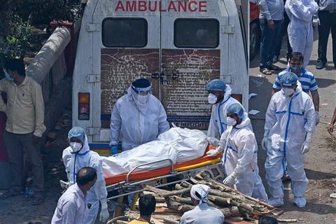 Nhân viên y tế chuyển thi thể bệnh nhân COVID-19 tới khu hỏa táng ở New Delhi, Ấn Độ. (Ảnh: AFP/TTXVN)