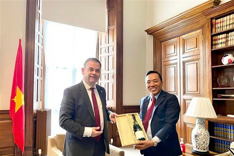 Quốc vụ khanh Nigel Adams trao quà tặng Đại sứ Nguyễn Hoàng Long. (Ảnh: TTXVN phát)