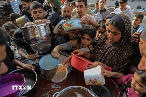 Người dân nhận thức ăn cứu trợ tại thành phố Rafah, Dải Gaza. (Ảnh: THX/TTXVN)