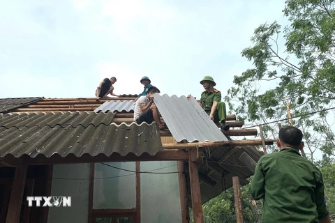 Lực lượng tại chỗ giúp các hộ gia đình lợp lại mái nhà. (Ảnh: TTXVN phát)
