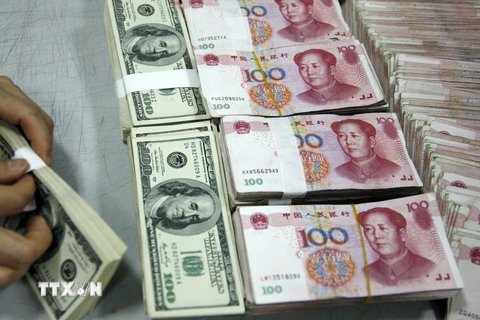 Nhân viên kiểm đồng USD và nhân dân tệ tại một ngân hàng ở tỉnh An Huy, Trung Quốc. (Ảnh: AFP/TTXVN)