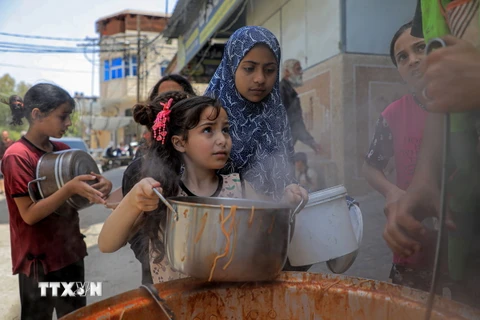 Trẻ em Palestine nhận thức ăn cứu trợ tại thành phố Rafah, Dải Gaza. (Ảnh: THX/TTXVN)