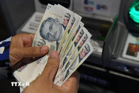 Người dân rút tiền đô la Singapore từ máy rút tiền tự động (ATM) tại Singapore. (Ảnh: AFP/TTXVN)