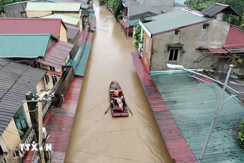 Lực lượng cứu hộ đưa người dân ra khỏi khu vực ngập úng tại đường Thanh Niên, phường Hồng Hà, thành phố Yên Bái. (Ảnh: Tuấn Anh/TTXVN)