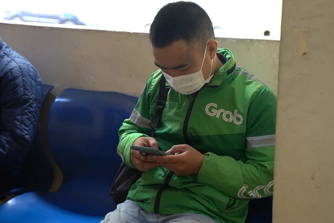 Anh Nguyễn Đức Nghiêm mệt mỏi chờ đợi xác minh lý lịch tư pháp để đăng ký chạy xe ôm công nghệ. (Ảnh: Lê Đức/Vietnam+)