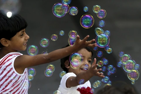 Hai em bé nhập cư đùa nghịch với bong bóng. (Nguồn: Dailymail)