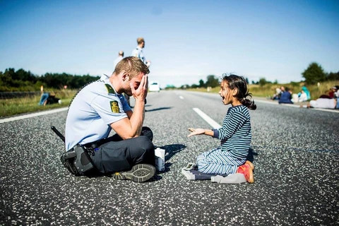 Cảnh sát Đan Mạch đang chơi đùa với bé gái Syria trên đường cao tốc ở miền Bắc Padborg, Đan Mạch khi gia đình em đang trên đường tới Thụy Điển ngày 9/9.