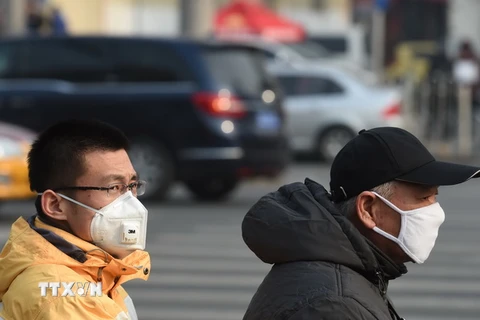 Người dân đeo khẩu trang đề phòng ô nhiễm không khí ở Bắc Kinh ngày 19/12. (Nguồn: AFP/TTXVN) 