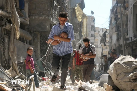 Chuyển các em nhỏ Syria ra khỏi một tòa nhà bị sập sau vụ không kích nhằm vào khu vực Salihin ở thành phố Aleppo, miền bắc Syria ngày 11/9. (Nguồn: AFP/TTXVN) 