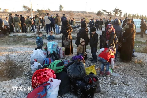 Nhân viên cứu hộ hỗ trợ người Syria sơ tán khỏi khu vực do phiến quân chiếm giữ ở Aleppo tới khu vực Khan al-Assal, phía tây thành phố ngày 15/12. (Nguồn: AFP/TTXVN) 