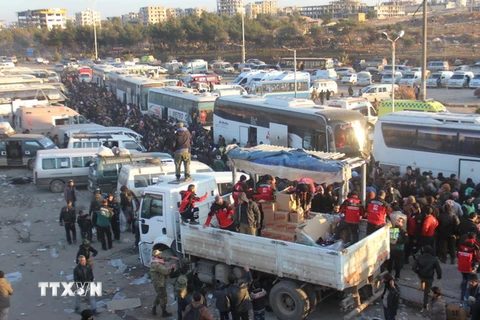 Các thành viên Cơ quan dân sự Syria phân phát hàng cứu trợ cho những người dân tại Khan al-Assal, phía tây Aleppo ngày 19/12. (Nguồn: AP/TTXVN)