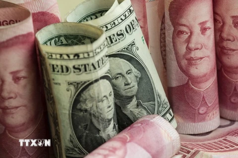 Tiền giấy mệnh giá 100 nhân dân tệ của Trung Quốc và đồng đôla Mỹ (giữa). (Nguồn: AFP/ TTXVN)