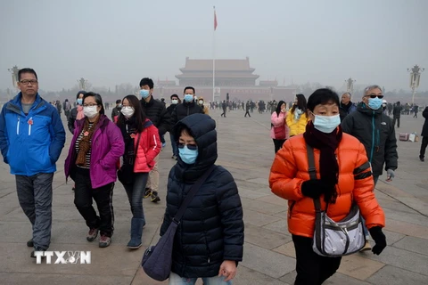 Người dân đeo khẩu trang để tránh ô nhiễm không khí tại quảng trường Thiên An Môn ở Bắc kinh, Trung Quốc. (Nguồn: AFP/TTXVN) 