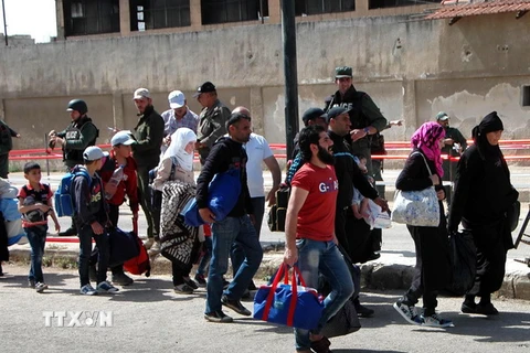 Các tay súng đối lập và gia đình sơ tán khỏi khu vực al-Waer, thành phố Hom, Syria ngày 10/5. (Nguồn: THX/TTXVN) 