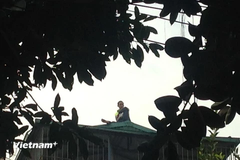 Thanh niên nghi ngáo đá cố thủ trên nóc nhà 4 tầng 10 giờ đồng hồ. (Ảnh: Sơn Bách/Vietnam+)